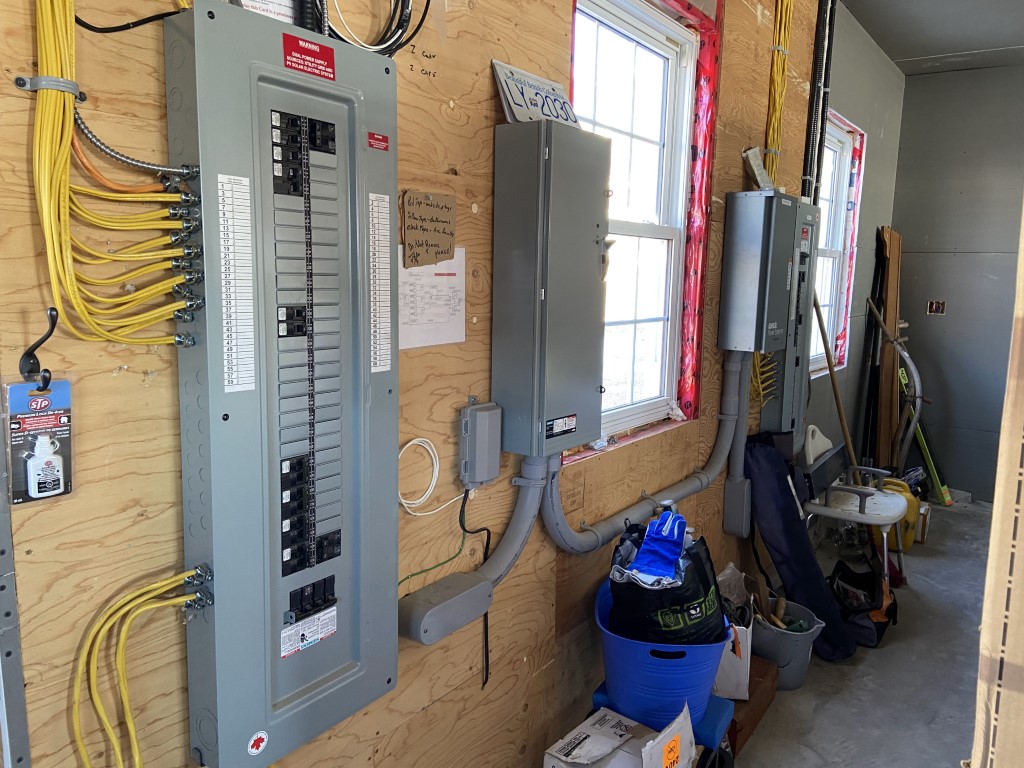 Neatly wired breaker panels and sub-panels installed on a garage wall
