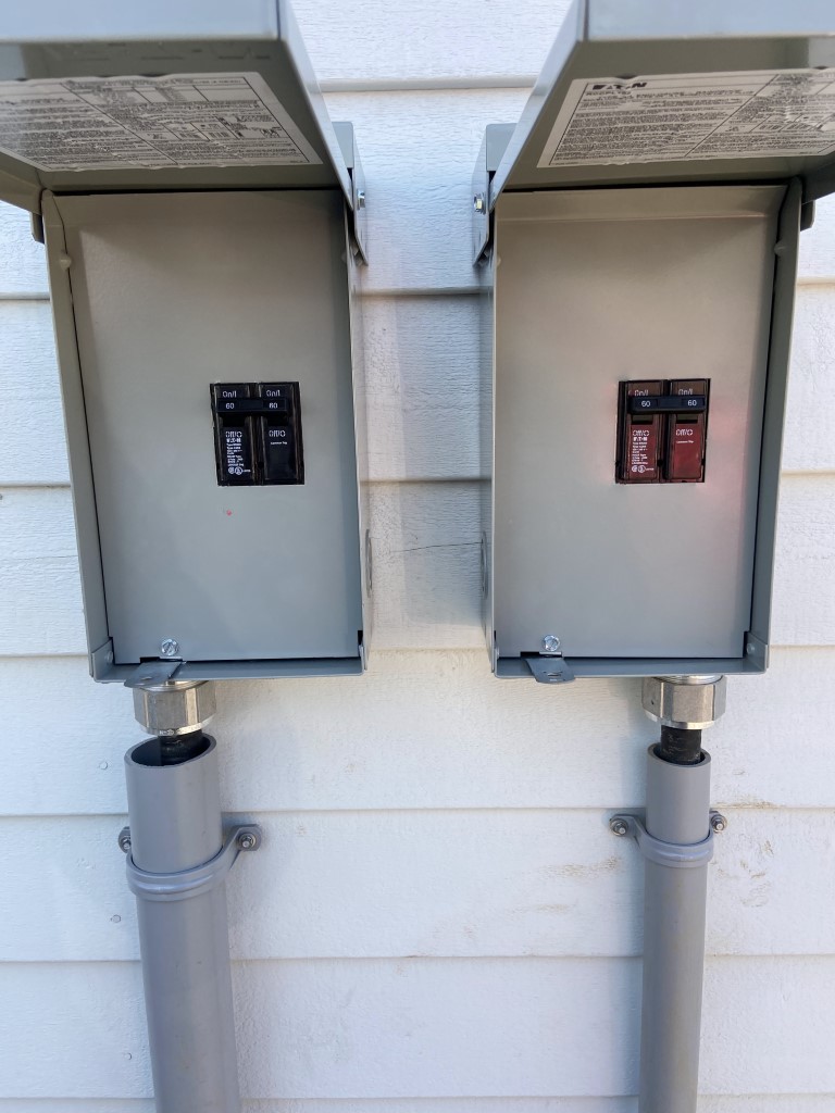 Pair of exterior electrical shut-off disconnect boxes in weatherproof enclosures